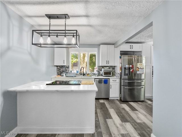 kitchen featuring dark wood-type flooring, decorative light fixtures, stainless steel appliances, and white cabinets