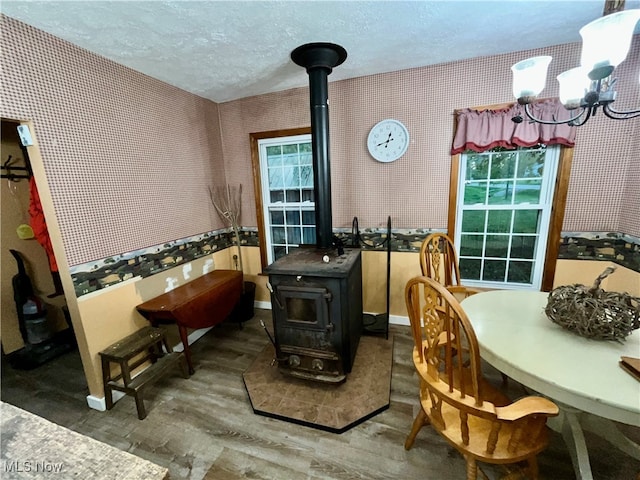 dining space featuring an inviting chandelier, hardwood / wood-style flooring, a textured ceiling, and a wood stove