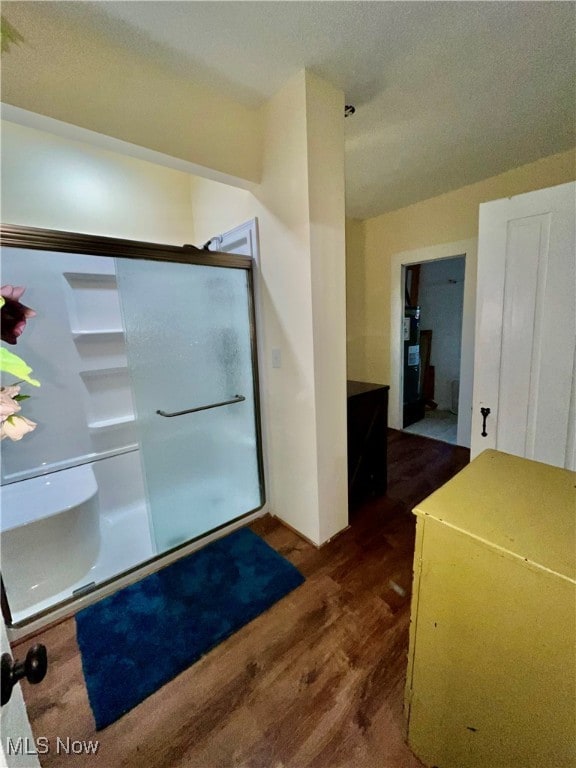 bathroom featuring wood-type flooring and a shower with shower door