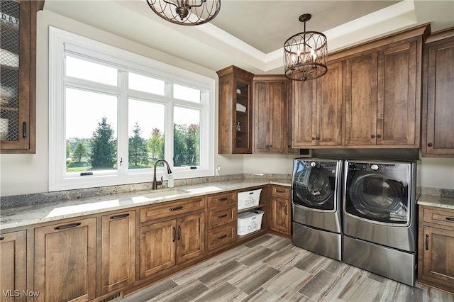 laundry area featuring independent washer and dryer, cabinets, a chandelier, and sink