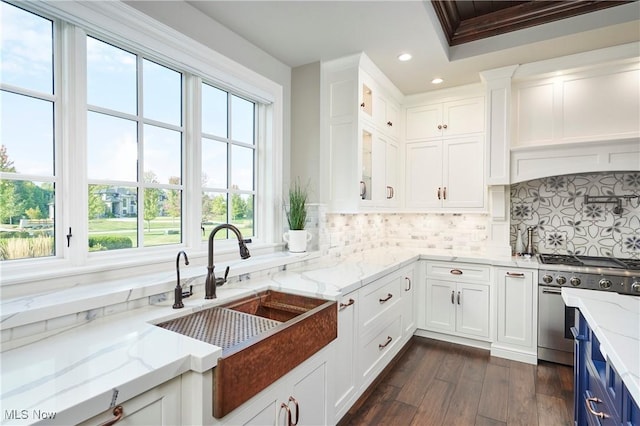 kitchen with sink, white cabinetry, high end range, backsplash, and light stone counters