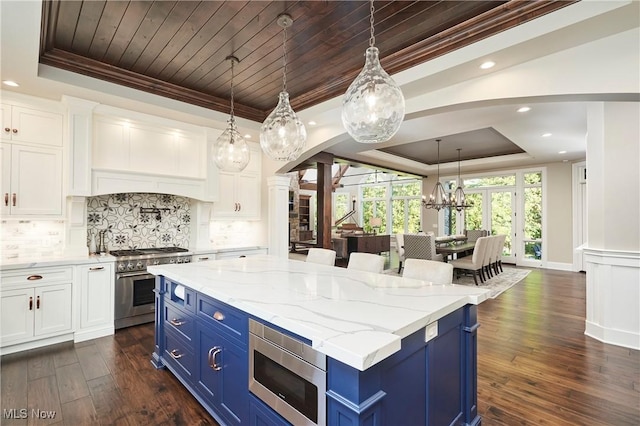 kitchen featuring a raised ceiling, white cabinetry, blue cabinets, and stainless steel appliances