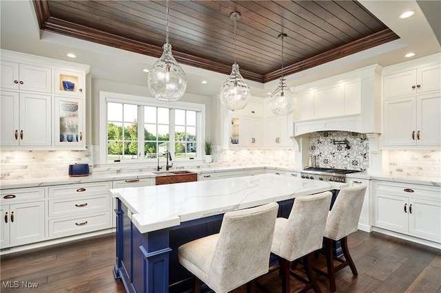 kitchen with white cabinetry, a center island, a raised ceiling, and wooden ceiling