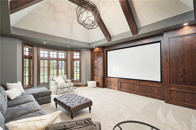 carpeted home theater with an inviting chandelier, beam ceiling, and high vaulted ceiling