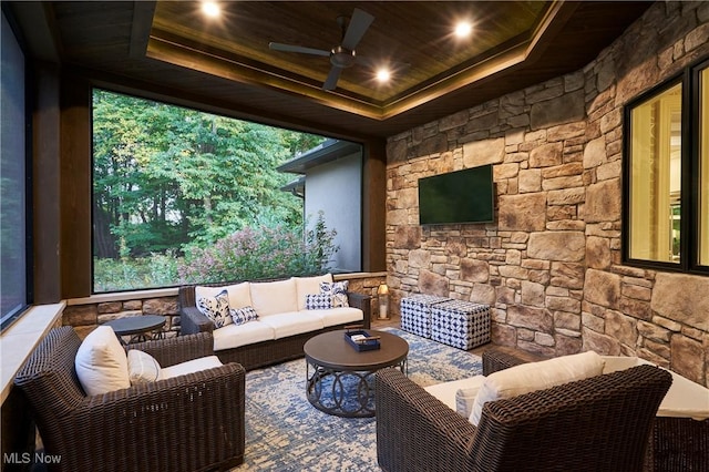 cinema with a healthy amount of sunlight, wooden ceiling, ceiling fan, and a tray ceiling