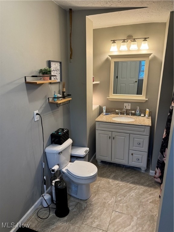 bathroom with vanity, toilet, and a textured ceiling