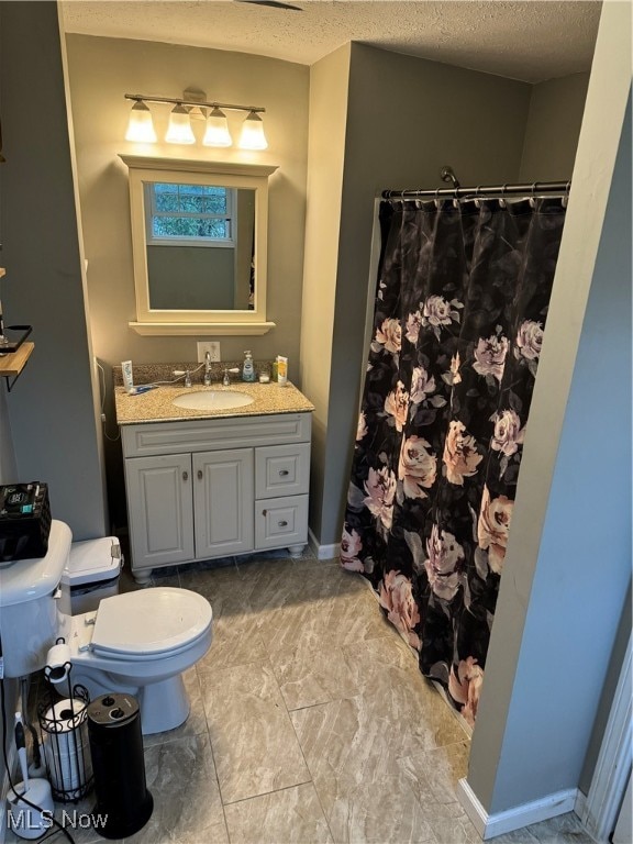 bathroom with a shower with curtain, vanity, toilet, and a textured ceiling