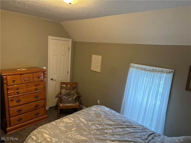 bedroom with lofted ceiling, dark colored carpet, and a textured ceiling