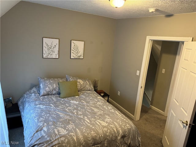 bedroom featuring carpet floors, vaulted ceiling, and a textured ceiling