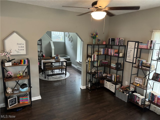 interior space with ceiling fan, dark hardwood / wood-style floors, and a baseboard heating unit