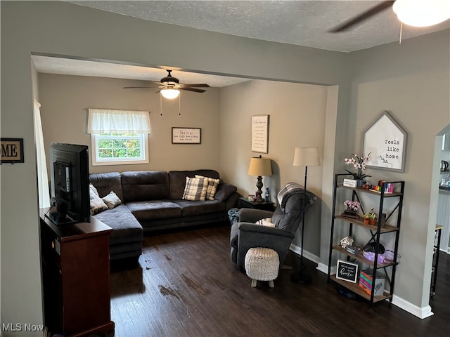 living room with ceiling fan, dark wood-type flooring, and a textured ceiling