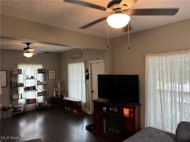 living room featuring ceiling fan, dark hardwood / wood-style floors, a textured ceiling, and a healthy amount of sunlight