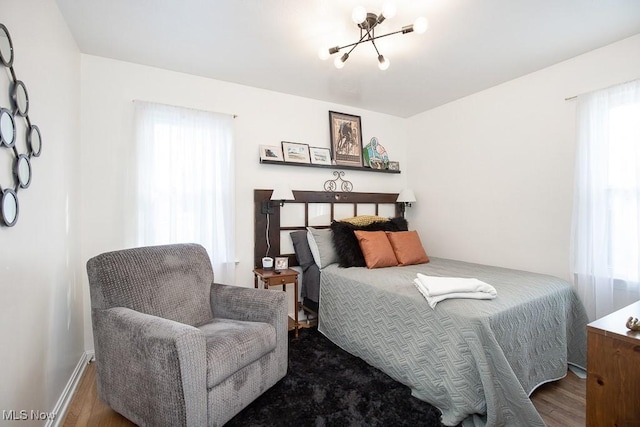 bedroom featuring multiple windows, a chandelier, and wood-type flooring