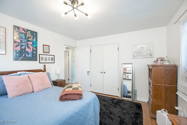 bedroom featuring a closet, a chandelier, and hardwood / wood-style flooring