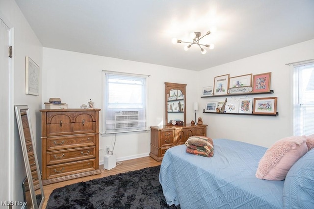 bedroom with a chandelier, hardwood / wood-style flooring, and multiple windows