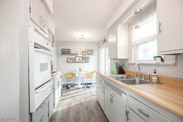 kitchen featuring white cabinets, dark hardwood / wood-style floors, hanging light fixtures, and sink