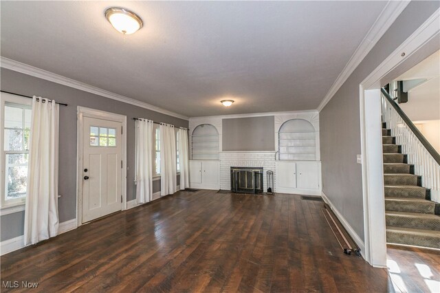 unfurnished living room featuring a brick fireplace, crown molding, and dark hardwood / wood-style floors