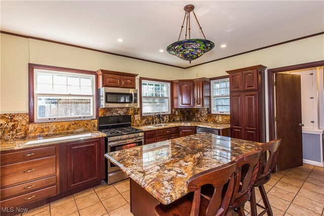 kitchen with light stone countertops, a center island, tasteful backsplash, hanging light fixtures, and appliances with stainless steel finishes