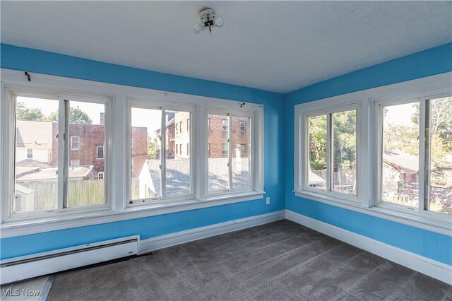 unfurnished sunroom with plenty of natural light and a baseboard heating unit