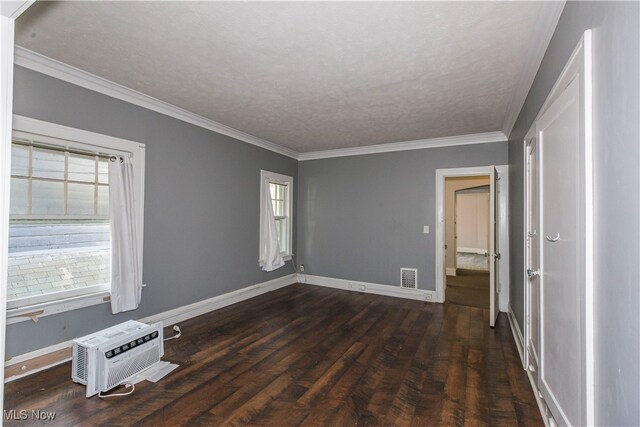 empty room featuring ornamental molding, a textured ceiling, an AC wall unit, and dark hardwood / wood-style flooring