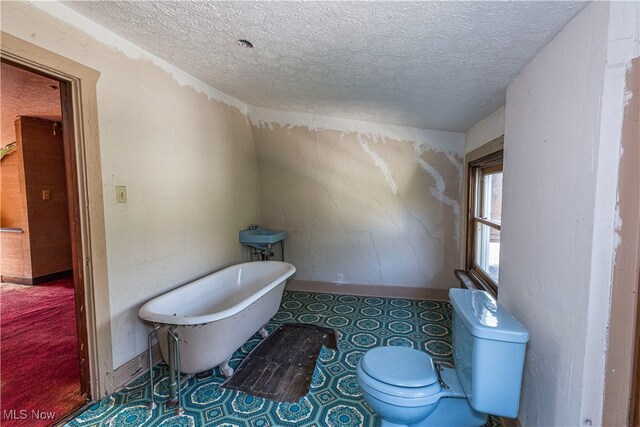 bathroom featuring a textured ceiling, a bathing tub, and toilet