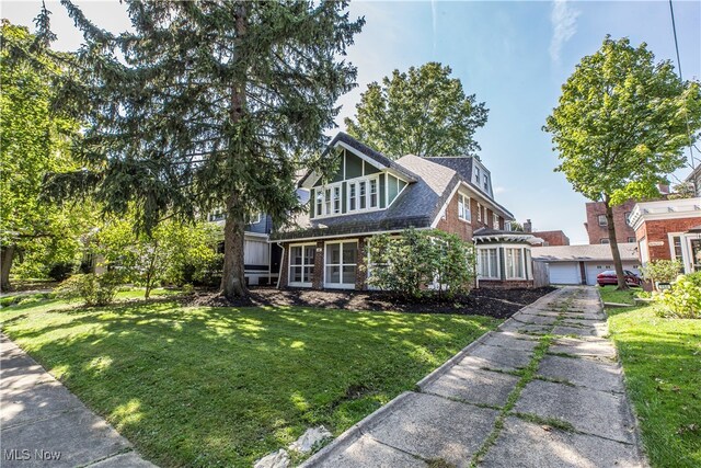 view of front of house featuring a front lawn, a sunroom, and a garage