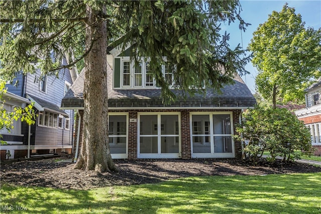 back of house with a sunroom and a lawn