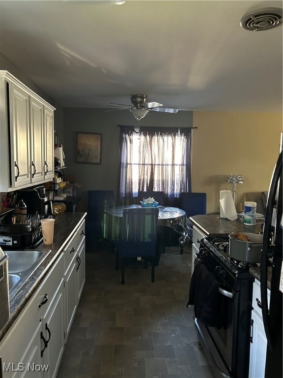 kitchen with sink, white cabinetry, white gas range oven, and ceiling fan