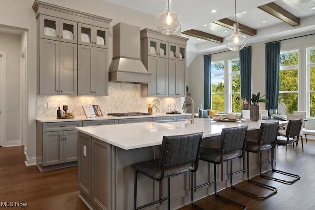 kitchen featuring beamed ceiling, a large island with sink, gray cabinets, dark hardwood / wood-style floors, and custom range hood