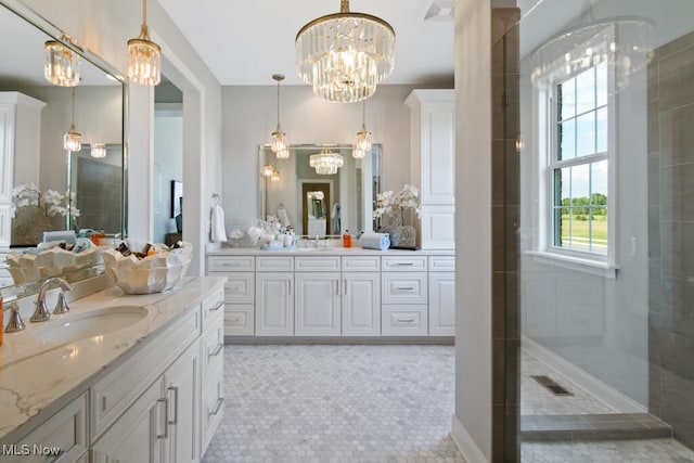 bathroom featuring tile patterned flooring, tiled shower, and vanity