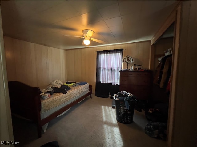 carpeted bedroom with ceiling fan and wood walls