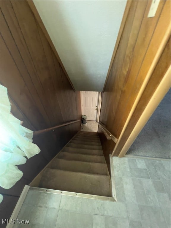 stairs featuring wooden walls, vaulted ceiling, and tile patterned floors