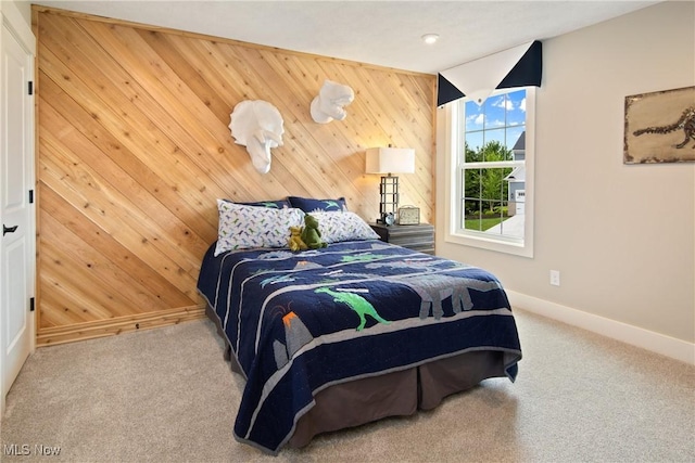 bedroom featuring carpet floors, baseboards, and wood walls