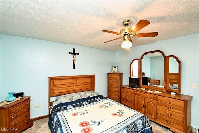 carpeted bedroom featuring ceiling fan and a textured ceiling