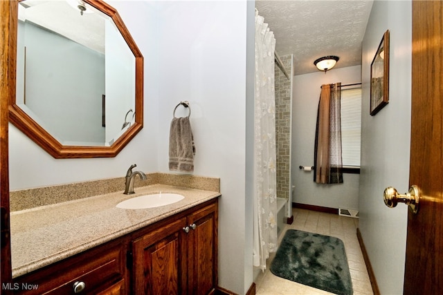 bathroom with tile patterned flooring, shower / tub combo with curtain, vanity, and a textured ceiling