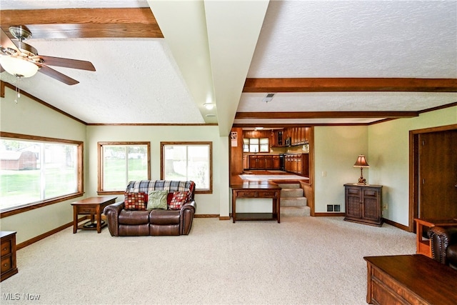 carpeted living room with ornamental molding, ceiling fan, vaulted ceiling with beams, and a textured ceiling