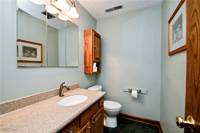 bathroom with vanity, toilet, a textured ceiling, and tile patterned floors