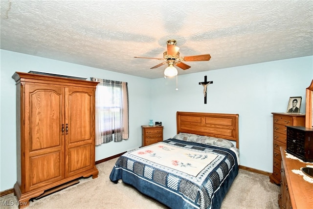 bedroom with ceiling fan, a textured ceiling, and light carpet