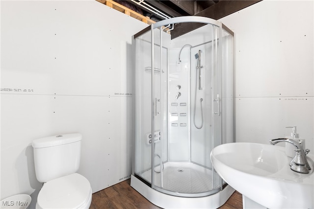 bathroom featuring hardwood / wood-style flooring, sink, a shower with door, and toilet