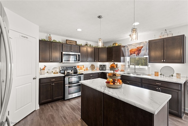 kitchen with a kitchen island, dark wood-type flooring, sink, pendant lighting, and appliances with stainless steel finishes