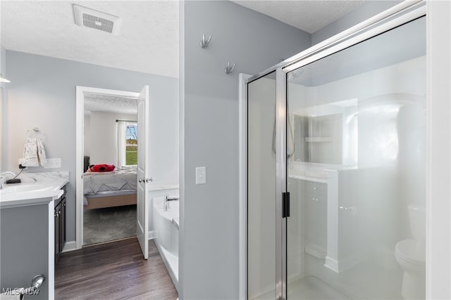 bathroom with vanity, hardwood / wood-style floors, a textured ceiling, walk in shower, and toilet