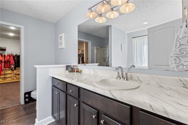 bathroom featuring vanity, an enclosed shower, wood-type flooring, a textured ceiling, and toilet