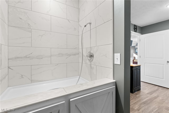 bathroom with tiled shower / bath combo, hardwood / wood-style flooring, and vanity