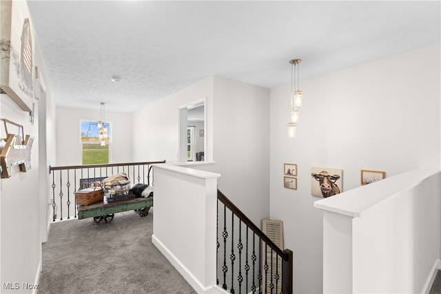 corridor with a textured ceiling and carpet flooring