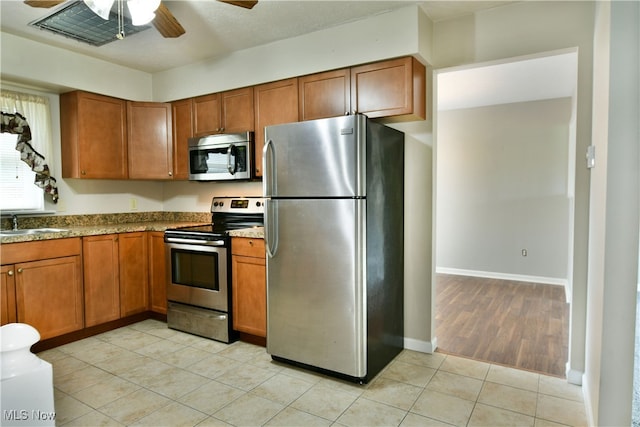 kitchen with appliances with stainless steel finishes, light wood-type flooring, ceiling fan, and sink