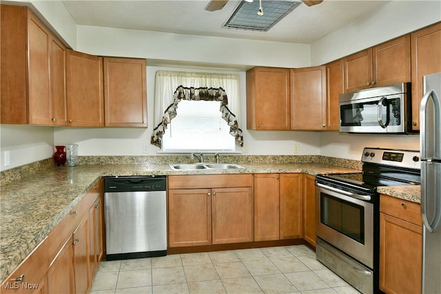 kitchen with stone counters, appliances with stainless steel finishes, sink, and light tile patterned floors