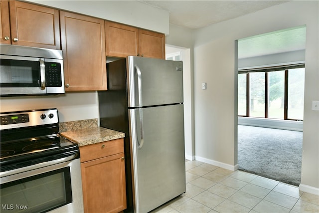 kitchen featuring stainless steel appliances, light stone countertops, and light tile patterned floors