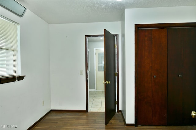 unfurnished bedroom featuring dark wood-type flooring, a closet, and a textured ceiling