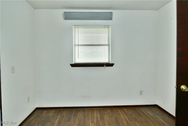 empty room with dark hardwood / wood-style floors and a wall unit AC