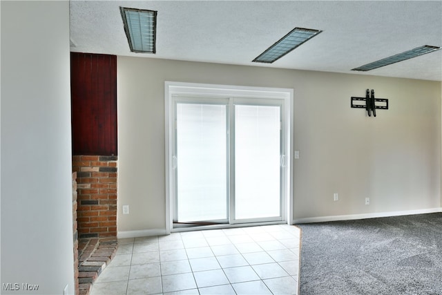 spare room with a textured ceiling and light tile patterned floors